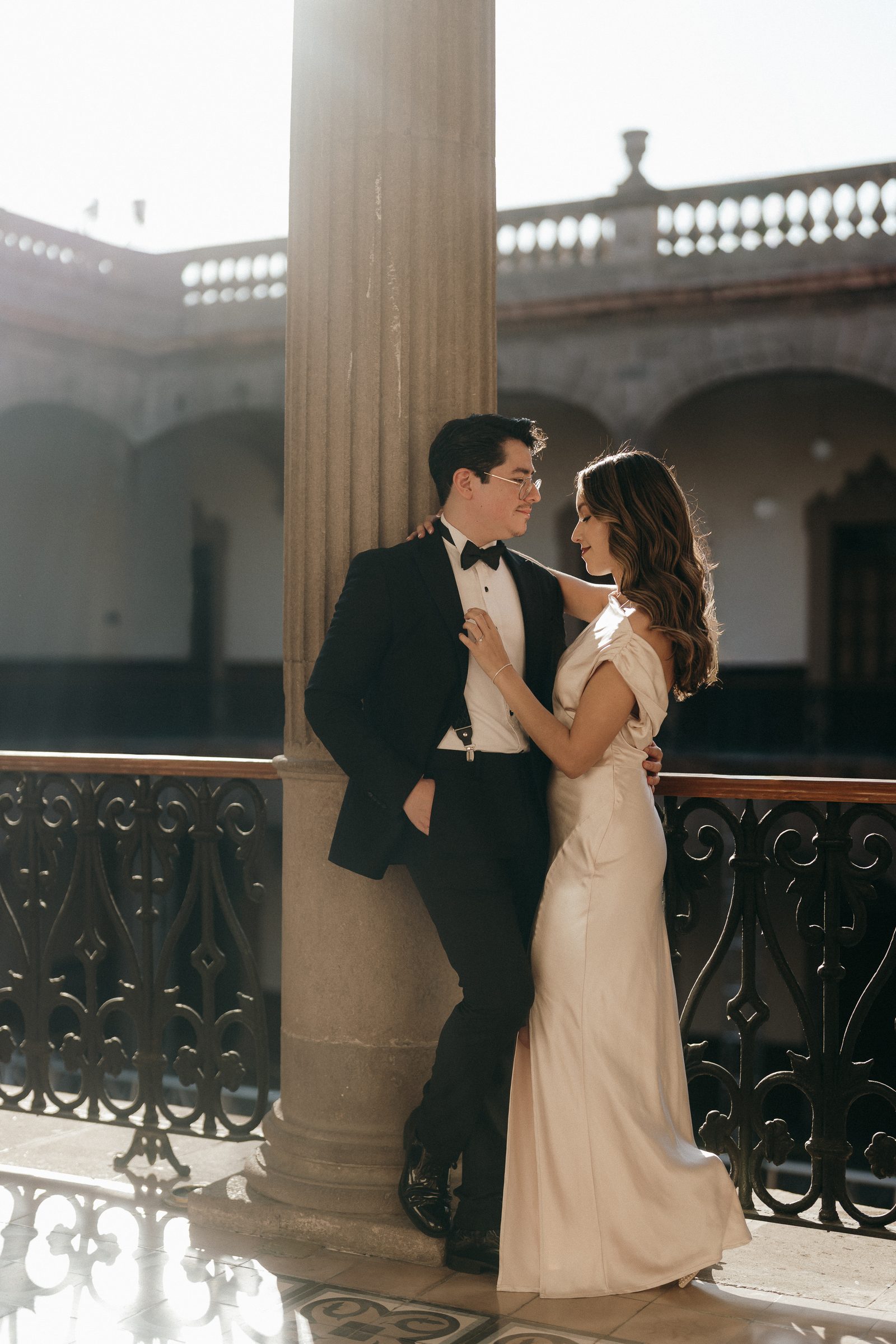 Los novios abrazados junto a una columna del patio
